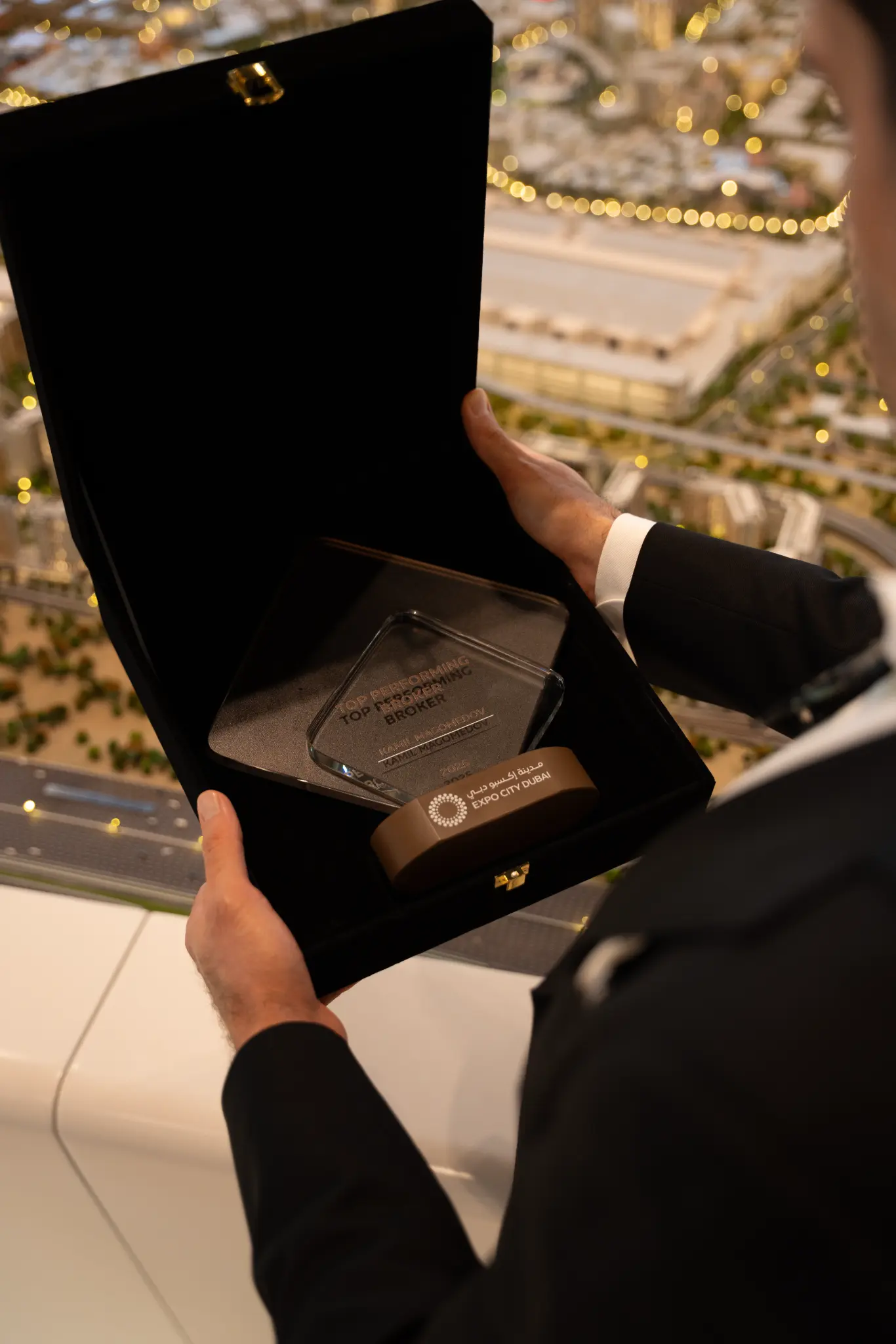 Kamil Magomedov holding the Expo City Dubai Top Performing Broker award presentation box, with the Expo City Dubai scale model visible in the background