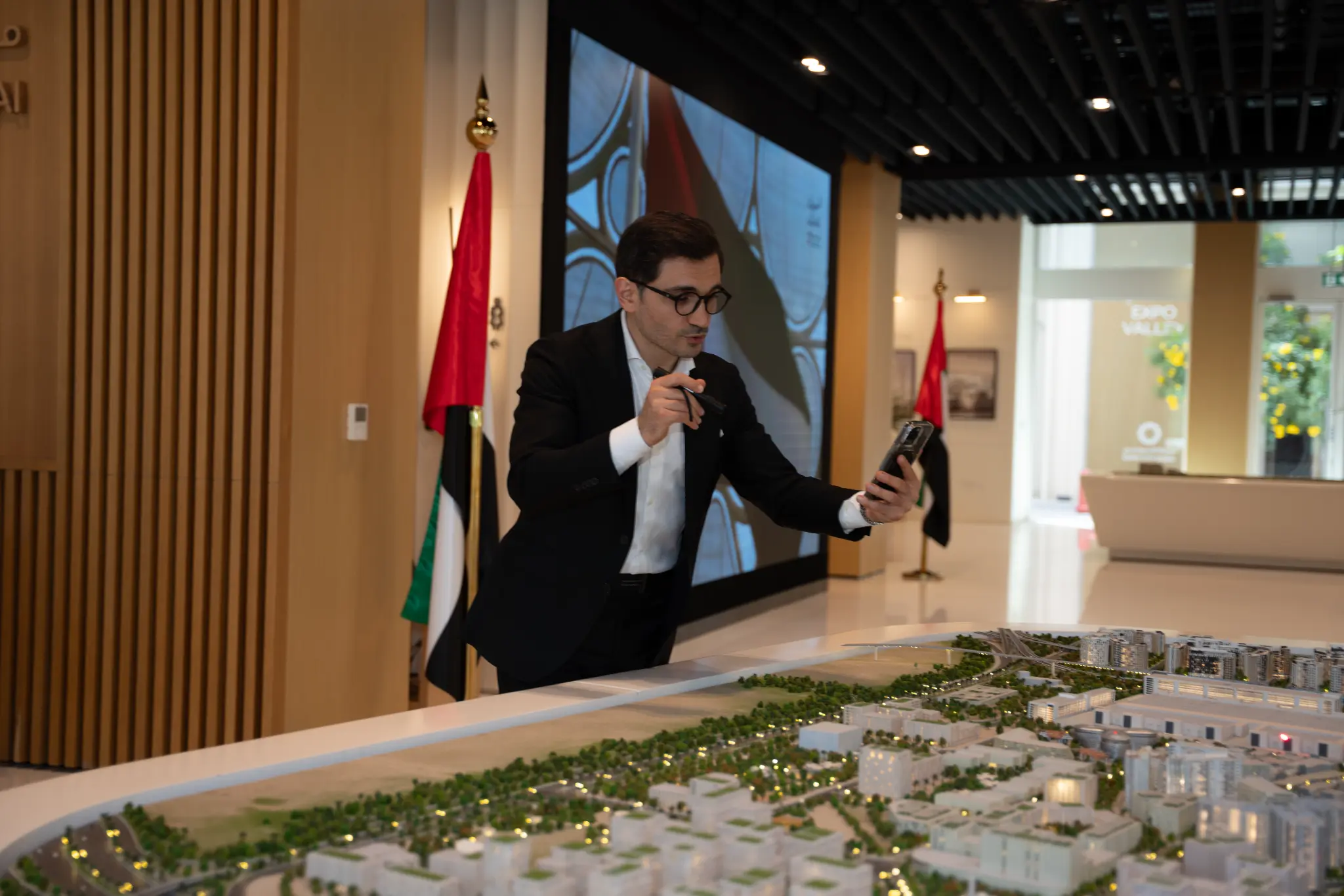 Kamil Magomedov studying the Expo City Dubai architectural scale model at the Expo City sales centre, UAE flag in background